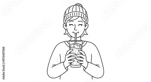 A cheerful person wearing a knitted winter hat and sweater happily sips a refreshing beverage through a straw in cold weather.
