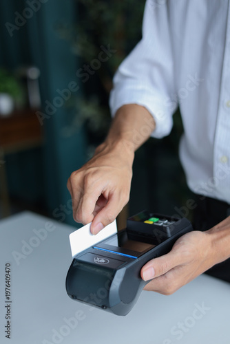 A person using a Point of Sale (POS) terminal to process a payment with a credit or debit card.