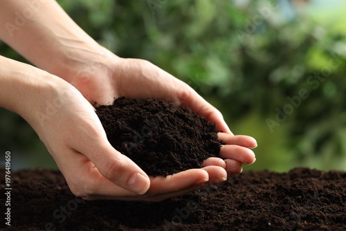 Woman with fresh soil on blurred background, closeup