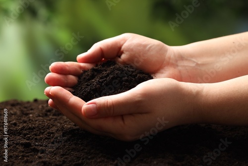 Woman with fresh soil on blurred background, closeup