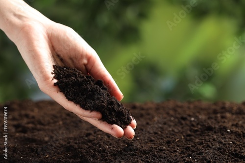Woman with fresh soil on blurred background, closeup
