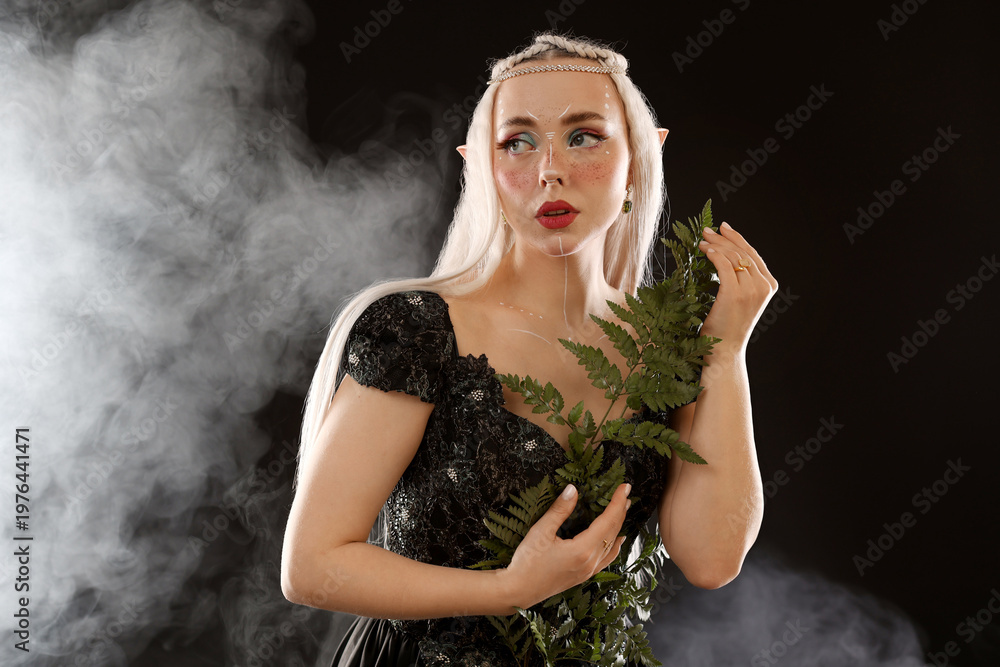 Obraz premium Beautiful elf girl with floral decor on black background with smoke