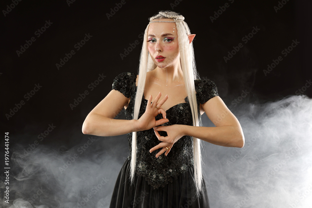 Obraz premium Beautiful girl dressed as elf on black background with smoke