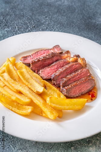 Sliced grilled beef steak with fries and chili sauce gourmet meal top view