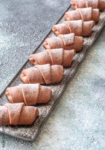 Chocolate croissants dusted with sugar on slate platter bakery top view composition