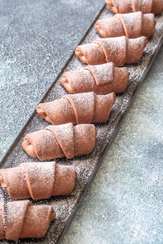 Chocolate croissants dusted with sugar on slate platter bakery top view composition