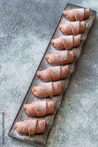 Chocolate croissants dusted with sugar on slate platter bakery top view composition