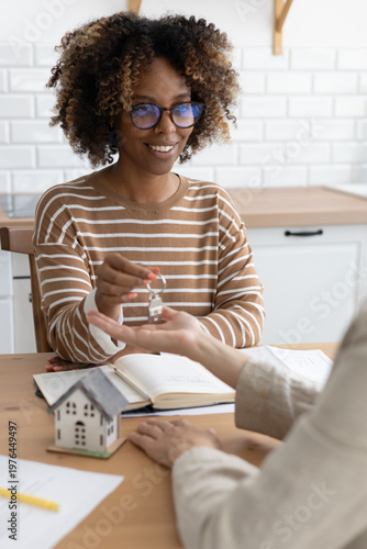 Close-up of happy woman realtor or property owner handing over key to house. concept of real estate transaction, buying real estate or renting apartment. New house, mortgage, collateral. 