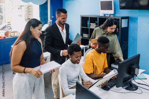 Diverse group of young university students and hispanic teacher using computer in an Academic Environment. Multicultural latin people in technology class in classroom in Latin America
