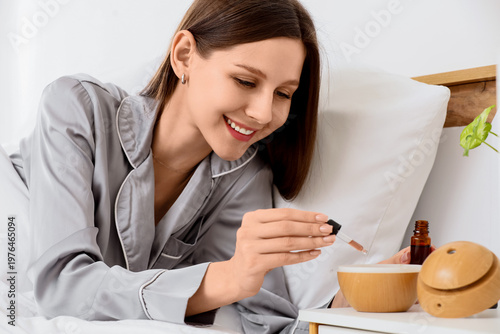Obraz na płótnie Young woman dropping essential oil into air humidifier in bedroom