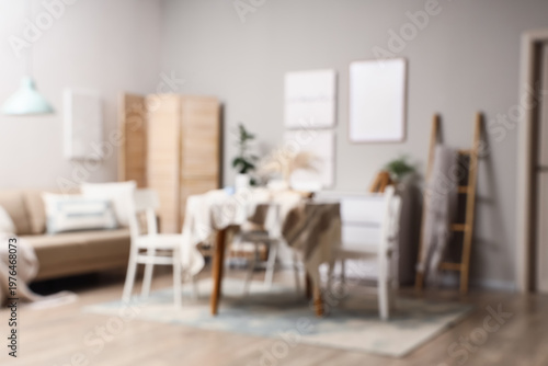 Blurred view of stylish dining room with table, sofa and folding screen