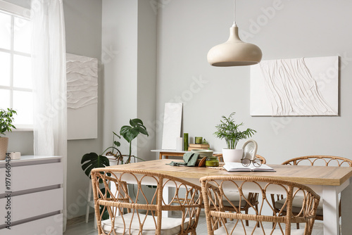Interior of light dining room with table, plants and paintings