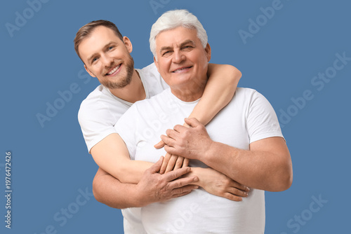 Senior man and his son hugging on blue background