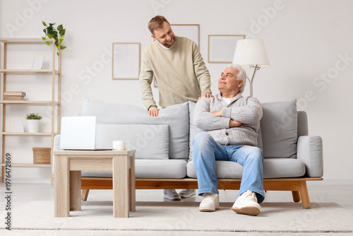 Senior man with his son sitting on sofa at home