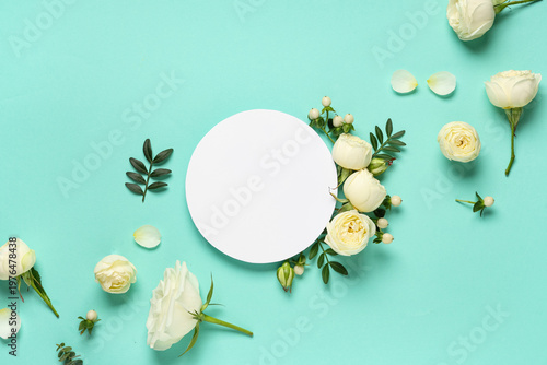 Blank card with beautiful white rose flowers and leaves on turquoise background
