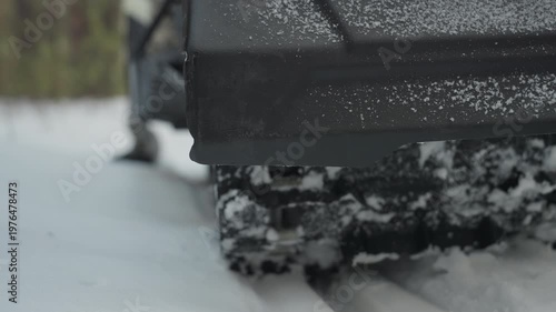 Closeup atv track churning snow, tight rear tread shot showing rubber lugs packed with ice, powder spray and frozen flakes, industrial texture of chassis, mechanic test vibe, low angle forest