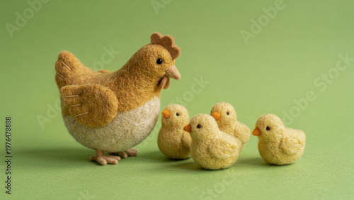 Needle felted wool sculpture of a hen and four chicks against a green background. Handmade textile art featuring soft plush farm animal crafts.
