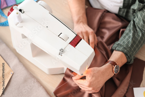 Young male tailor using sew...