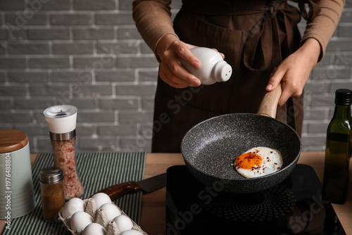 Woman adding salt into fryi...