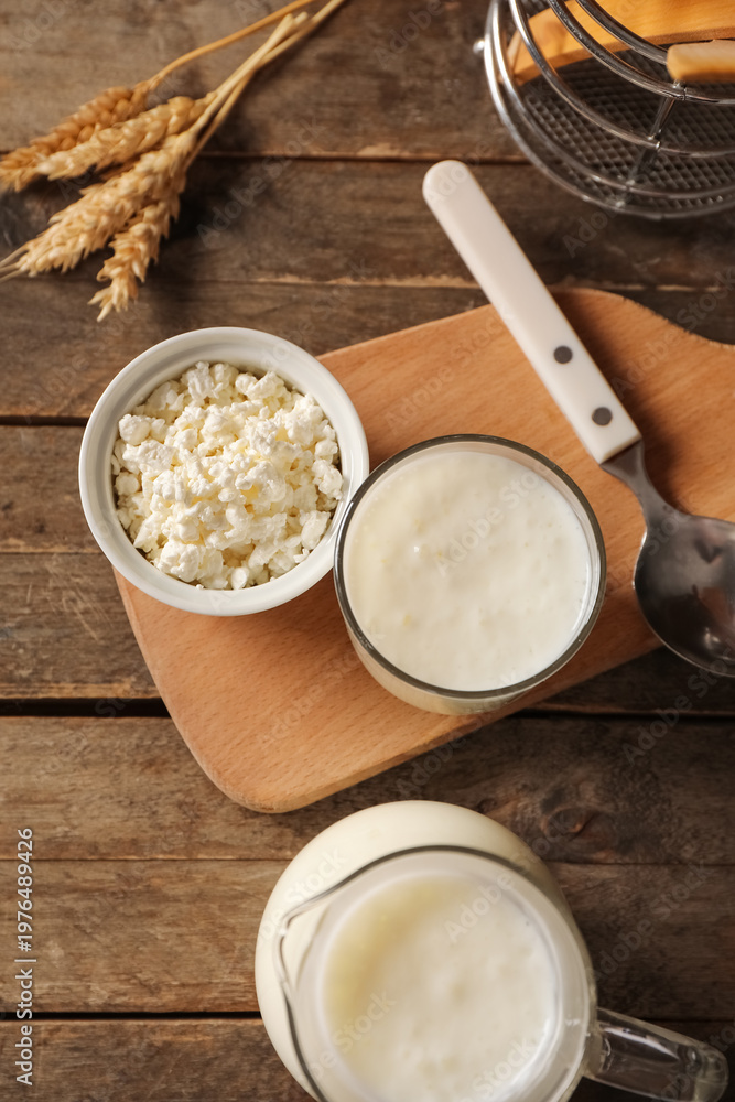Naklejka premium Glass of fresh kefir with wheat and bowl of cottage cheese on wooden background