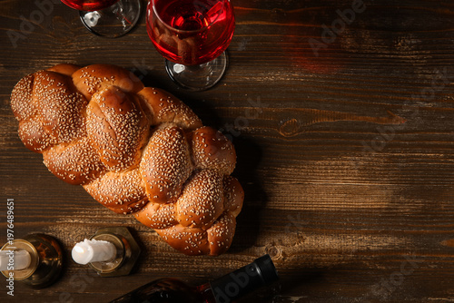 Foto Traditional challah bread with wine and burning candles on wooden table