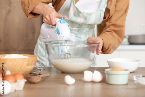 Young woman using mixer at ...