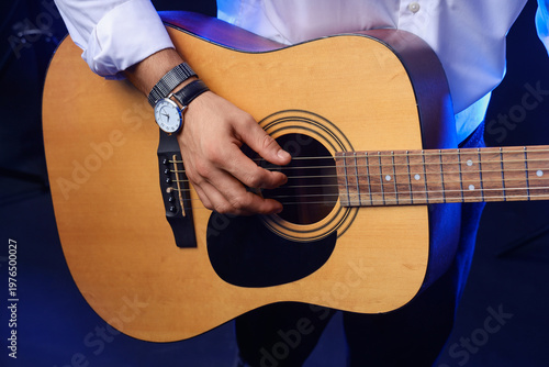 Fotografie Young man playing guitar on black background