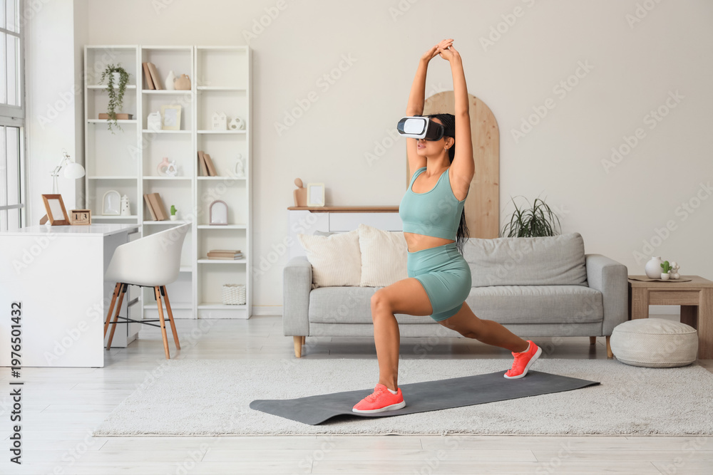 Obraz premium Sporty African-American woman in VR glasses training on mat at home