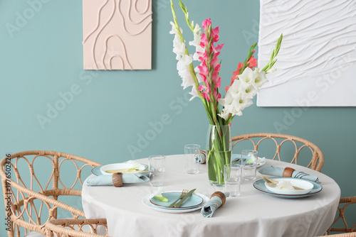 Elegant table setting with plates, glasses and beautiful gladiolus flowers