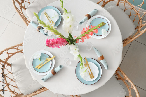 Elegant table setting with plates, golden cutlery and beautiful gladiolus flowers, top view