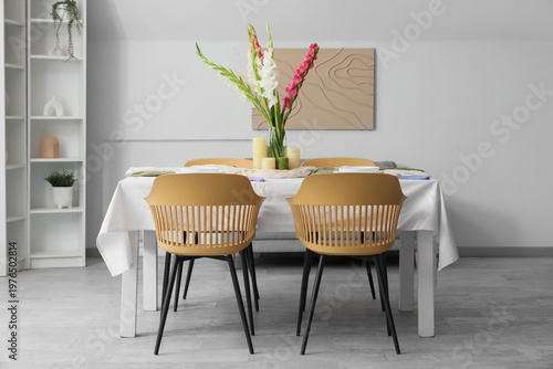 Served dining table with plates and beautiful gladiolus flowers in interior of stylish dining room