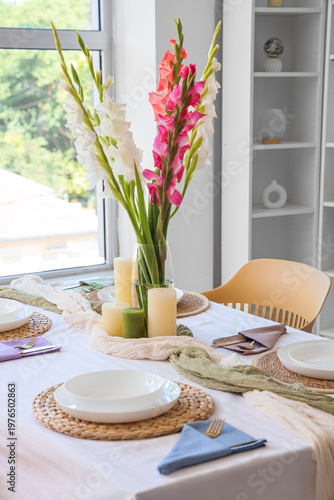 Elegant table setting with plates, candles and beautiful gladiolus flowers
