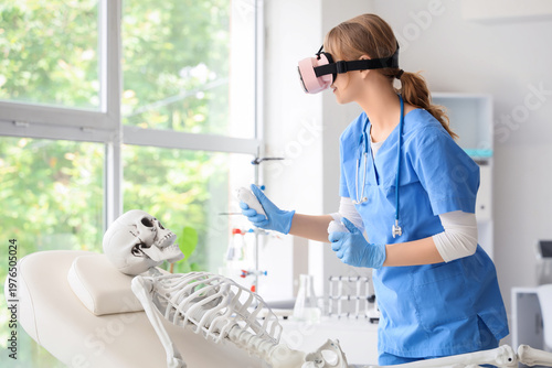 Female doctor using VR glasses with controllers and human skeleton model at h...