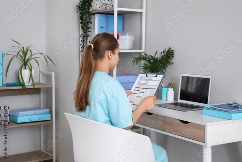 Young female doctor examining results of laboratory test at table in clinic