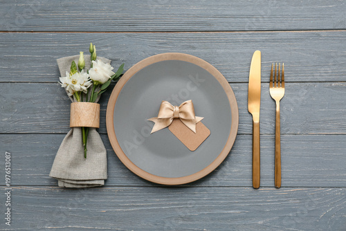 Stylish table setting with bow and beautiful flowers on grey wooden background