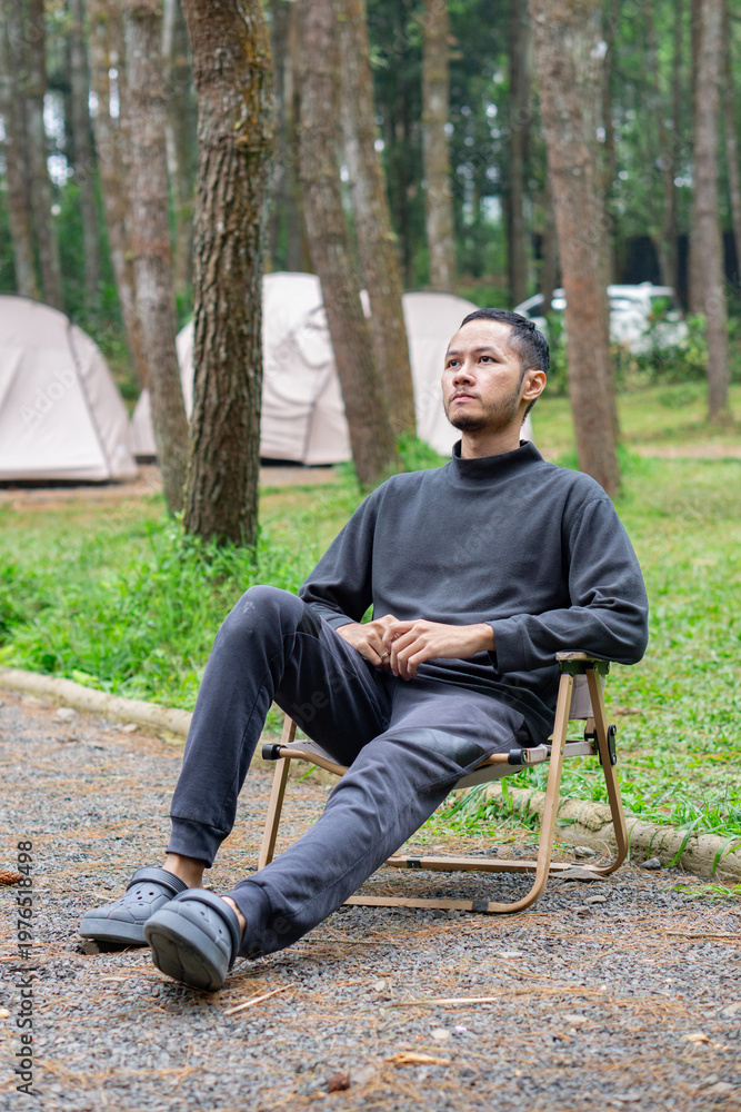 Obraz premium A man sitting relaxing on camp site in the forest