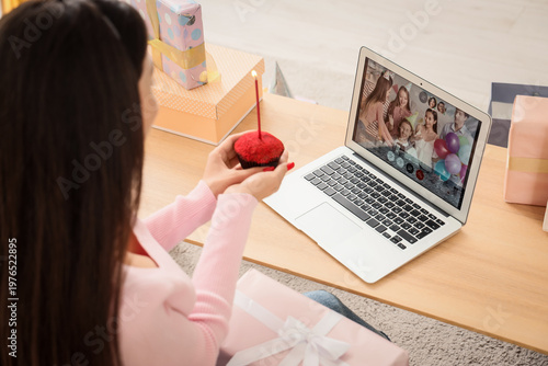 Young woman with muffin and laptop celebrating Birthday online at home, closeup
