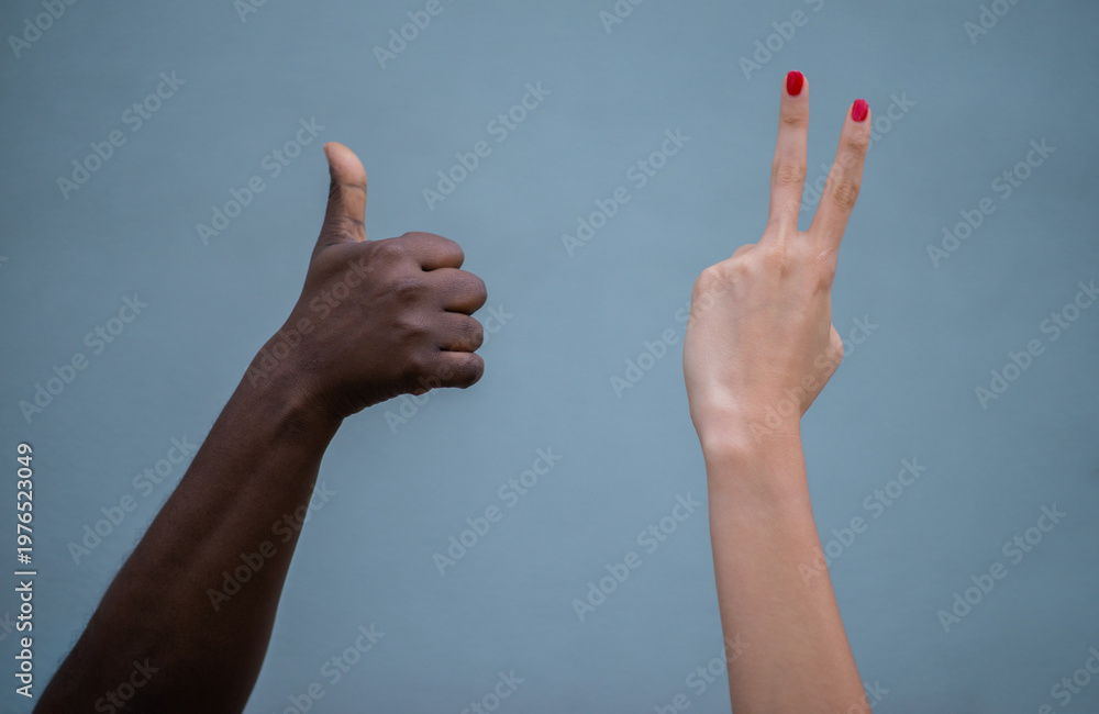 © Manuela - Manos de diferentes tonos de piel haciendo gestos de aprobación y paz sobre fondo neutro, concepto de diversidad e inclusión