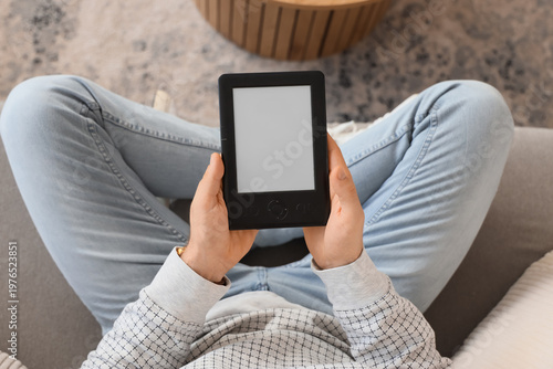 Young man with e-reader sit...