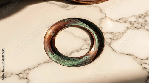 old weathered copper ring with green patina, top view on marble surface, vintage metal circle, aged material