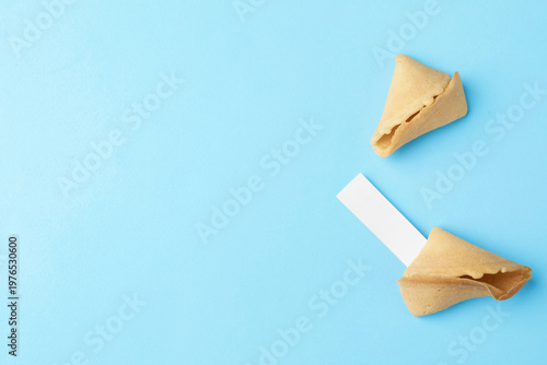 Tasty fortune cookie with prediction on light blue background, top view. Space for text