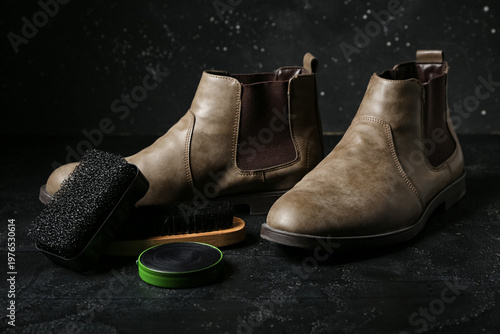 Boots, brushes and shoe polish on black background
