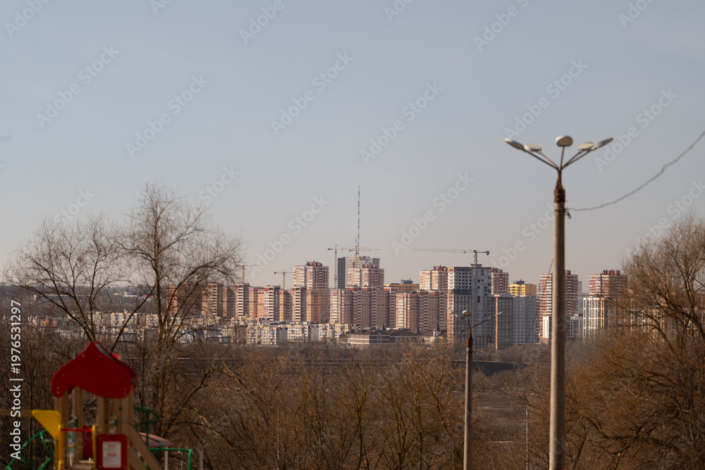 Fototapeta premium Empty playground with distant skyline backdrop, red play structure beside bare branches, quiet morning mood, imagined groundskeeper inspection, maintenance ready scene