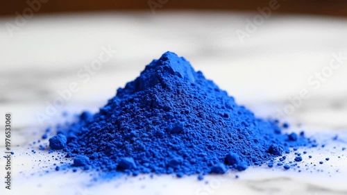 Pile of vibrant electric blue pigment powder, detailed texture and fine particles, isolated on a marbled surface with soft focus background