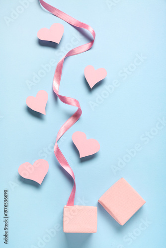 Composition with box, ribbon and pink paper hearts on color background. Valentines Day celebration