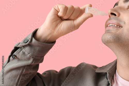 Young man using nasal drops...