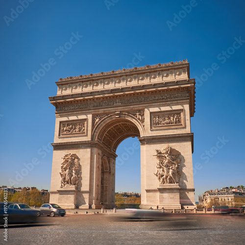 Arc de Triomphe framed by clear blue sky and bustling traffic in spring