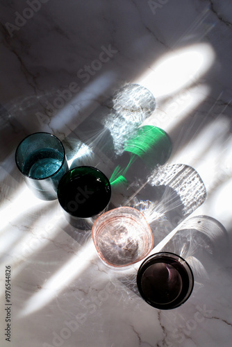 Colorful glass of water under sunlight reflection on white background. Minimal modern background.

