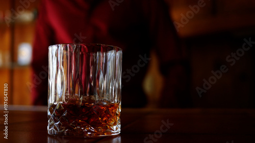 Male Bartender sets down a Glass of Whiskey in Trendy Bar
