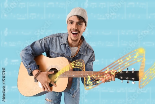 Happy young man playing guitar on light blue background